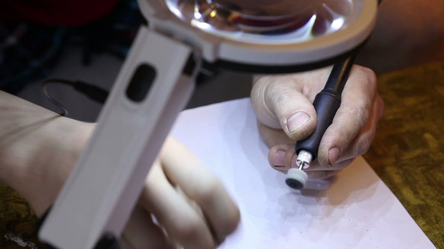 jeweler polishing gold ring with the help of a drill.