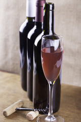 glass of rose wine, corkscrew on the background bottles