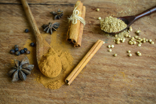 Cinnamon sticks, star anise and coriander powder on wooden table