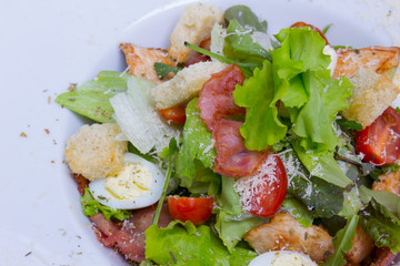 Caesar salad with chicken and quail eggs, closeup