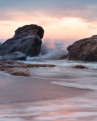 Splashes of sea wave between the stones in the sun on the beach.
