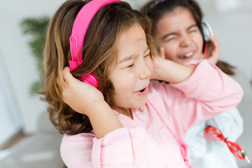 Two young sisters listening to music and dancing at home.