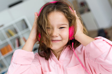 Beautiful child listening to music and dancing at home.