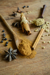 Cinnamon sticks, star anise and coriander powder on wooden table