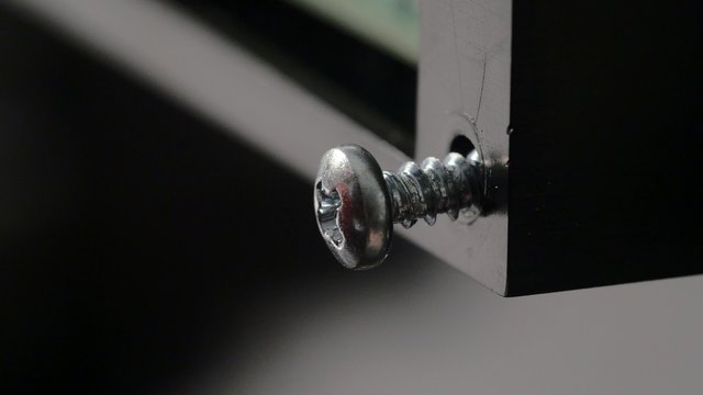 Tightening a silver screw with a screwdriver