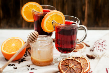 
mulled wine with oranges , honey , cinnamon and cloves on a wooden background   