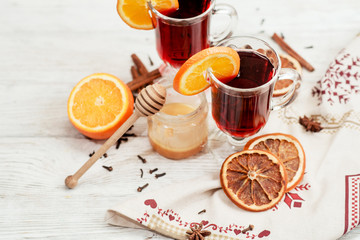 
mulled wine with oranges , honey , cinnamon and cloves on a wooden background   