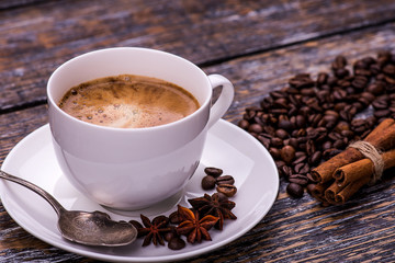 Coffee cup and beans on a wooden table. Dark background.
