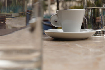 Espresso cup between two glasses on a marble table in a cafe