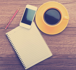 notebook with pen, smart phone and coffee cup on wooden backgrou