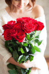 Obraz na płótnie Canvas beautiful girl with big red roses bouquet