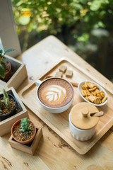 hot latte art  with cactus in coffee shop on table wooden