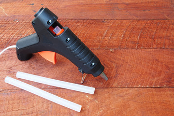 Electric hot glue gun on a wood background