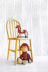 Old well-loved monkey toy and Christmas horse on an old wooden child chair.