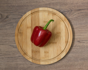 Fresh raw pepper food. Red paprika on the bamboo cutting board. Brown wood imitating background