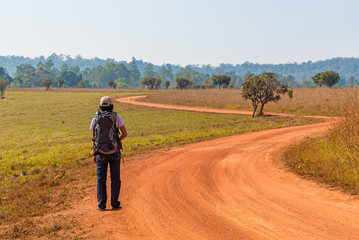 Fototapeta na wymiar Woman Traveler with Backpack on dirt road.