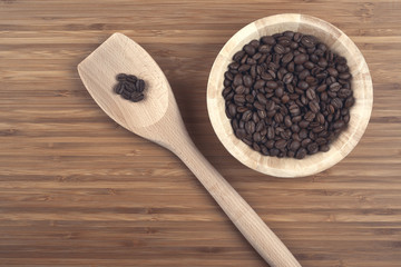 Coffee beans in bowl on wooden background