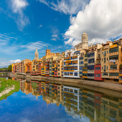 Colorful yellow and orange houses and famous house Casa Maso reflected in water river Onyar, in Girona, Catalonia, Spain. Church of Sant Feliu and Saint Mary Cathedral at background.