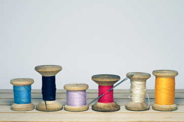 Old spool of thread with needle closeup. Tailor's work table. textile or fine cloth making.