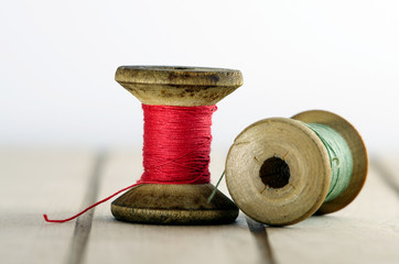 Vintage spool of thread with needle closeup. Tailor's work table, textile or fine cloth making.