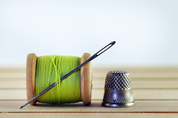 Vintage spool of thread with needle closeup. Tailor's work table, textile or fine cloth making.