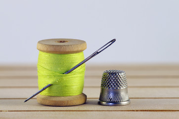 Vintage spool of thread with needle closeup. Tailor's work table, textile or fine cloth making.