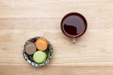 Obraz na płótnie Canvas Glass cup of black tea and colorful macarons
