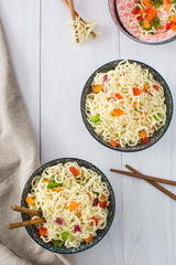 Asian noodles and vegetables on a white wood
