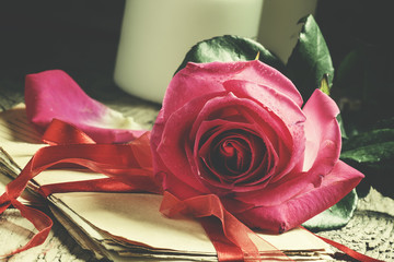 Vintage composition with fresh pink rose, a bundle of old letter