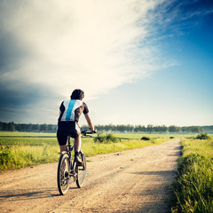 Fototapeta premium Cyclist Riding a Bike on the Country Road