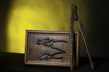Ancient joiner equipment : compass and pliers for saw. Yellow and black background