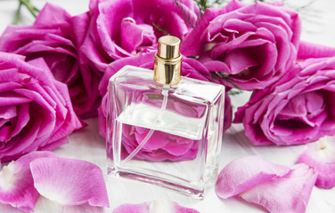 Roses perfume in transparent bottle with pink roses and petals
