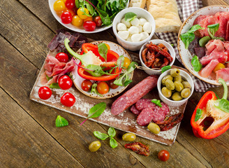 Appetizer set. Tomatoes, Meat, vegetables and cheese on wooden b