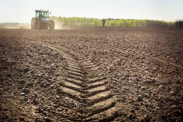Foto op Canvas distant tractor closeup fresh track on wet spring ground © SlavaStock