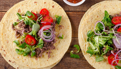 Two mexican tacos on rustic wooden table.