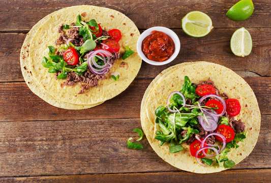 Two mexican tacos on rustic wooden background.
