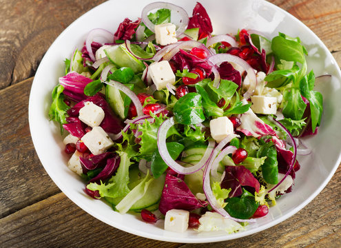 Fresh green salad with feta, onion and pomegranate.