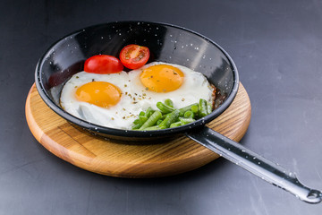 Fried egg on a pan served with tomato and asparagus