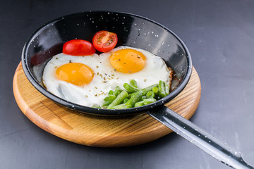 Fried egg on a pan served with tomato and asparagus