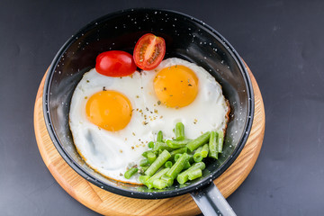 Fried egg on a pan served with tomato and asparagus