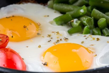 Fried egg on a pan served with tomato and asparagus