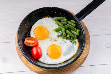 Fried egg on a pan served with tomato and asparagus