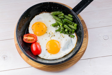 Fried egg on a pan served with tomato and asparagus