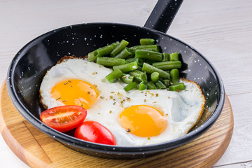 Fried egg on a pan served with tomato and asparagus