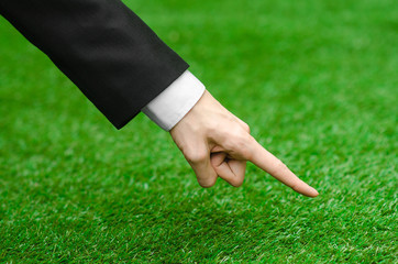 Nature and business topic: the hand of man in a black suit indicates green grass