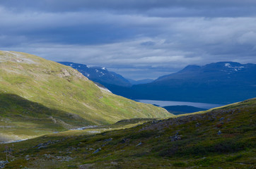 Fototapeta na wymiar River meandering through a green tundra valley in the mountains, Abisko, subarctic Swedish Lapland