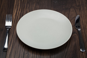 Empty Plate, Fork, Knife on wooden background. Top View with Text Space
