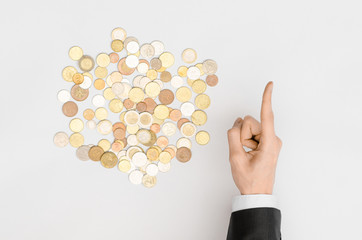 Money and Finance Topic: Money coins and human hand in black suit showing gesture on a gray background top view