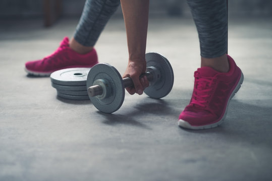 Closeup on woman lifting dumbbell from the floor