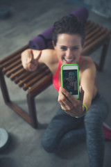 Closeup on fitness woman sitting in loft gym and taking selfies